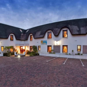 Thatched manor house frontage of the Oakhurst Hotel in central George at dusk