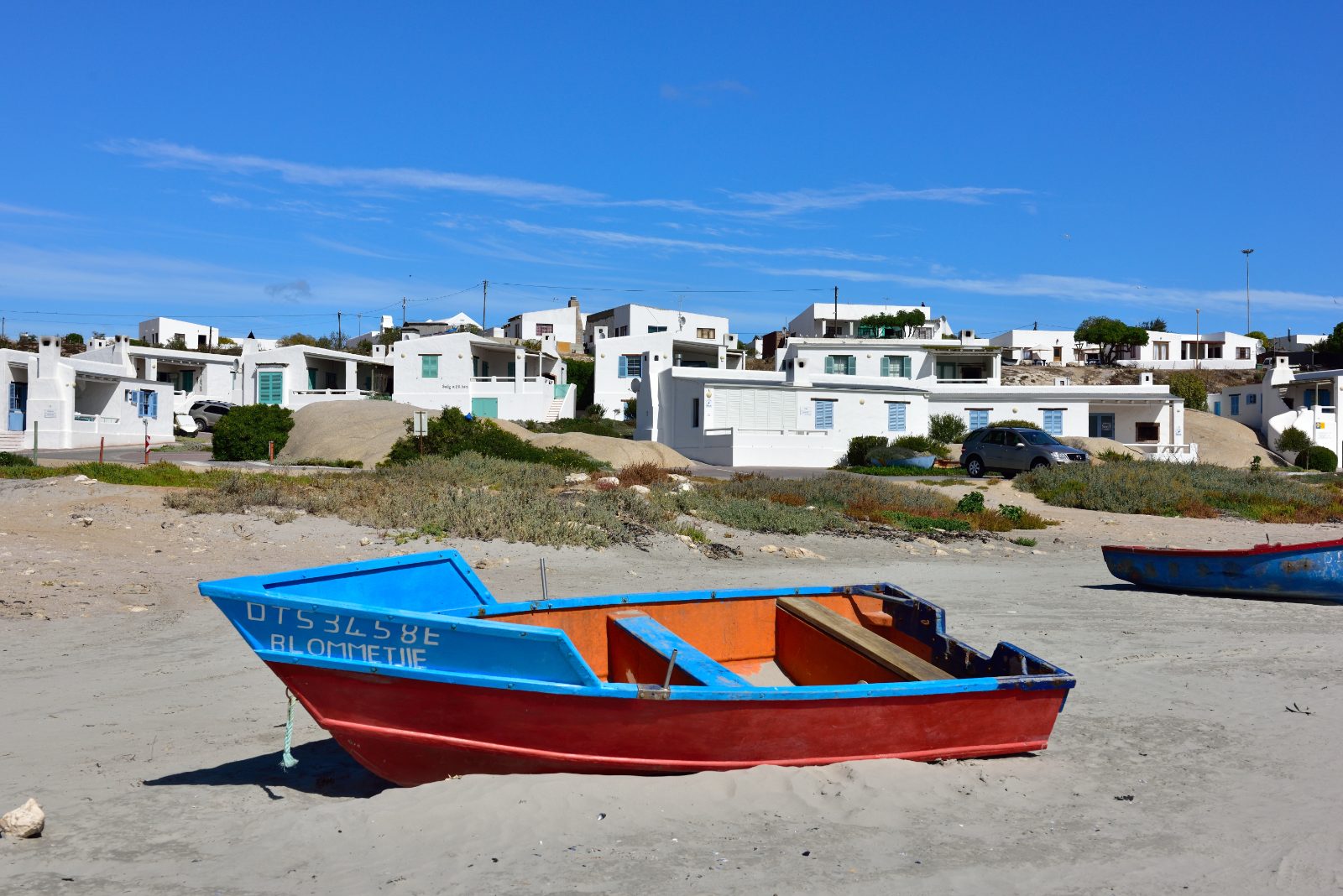Painted fishing boats drawn up on the sand in front of whitewashed cottages at Paternoster