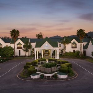 Gabled entrance and gardens of the Protea Hotel George King George at dusk