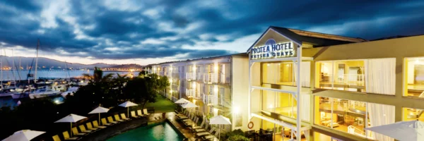 El Protea Hotel Knysna Quays iluminado al anochecer junto a la laguna y el puerto deportivo de Knysna