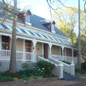A gabled house with a decorated veranda on a street in Swellendam