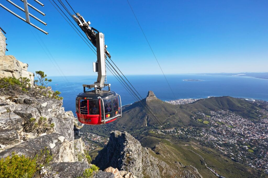 A cable car on the Table Mountain Aerial Cableway with Lion’s Head and the city below