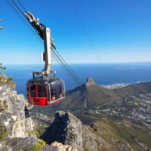 A cable car on the Table Mountain Aerial Cableway with Lion’s Head and the city below