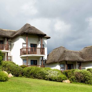 Thatched hotel buildings and lawns at Whalesong Hotel above Plettenberg Bay