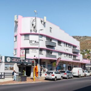 A pink building with cars parked in front of a street at 55 on Main Guesthouse and Spa in Fish hoek