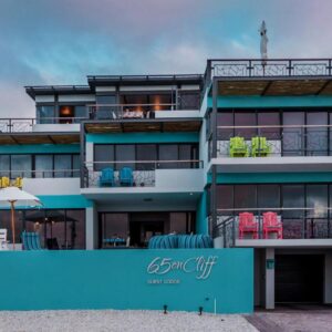 A blue building with chairs on the balcony at 65onCliff in Gansbaai
