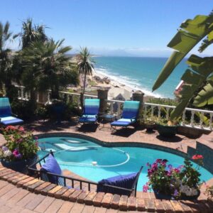 A swimming pool with chairs and the beach at A Heavenly View in Muizenberg