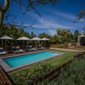 A pool with chairs and umbrellas in a yard at A Hilltop Country Retreat in Swellendam