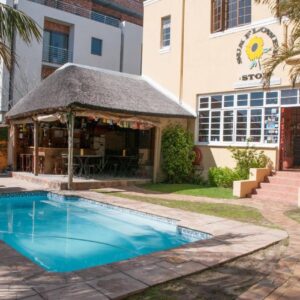 A swimming pool with a gazebo next to a building at A Sunflower Stop Backpackers in Cape Town