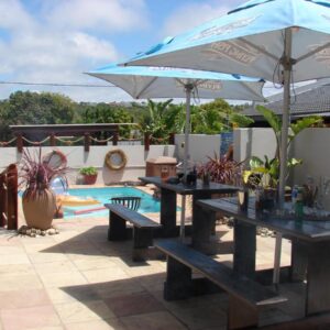 Two picnic tables with an umbrella next to a pool at A Time And A Place in Plettenberg Bay
