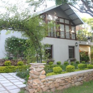 A house with a stone wall and a balcony at Aan De Vliet Guest House in Stellenbosch
