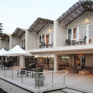 A house with a deck with tables and umbrellas at Abalone Guest Lodge in Hermanus
