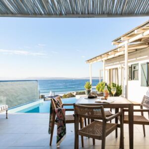 A balcony with a table and chairs and a view of the ocean at Abalone Hotel & Villas in Paternoster