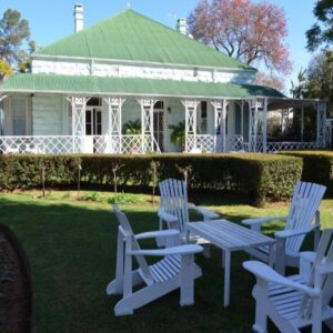 Three white chairs and a table in front of a white house at Adley - House in Oudtshoorn