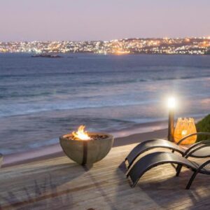 A table with two fires on the beach at night at African Oceans Manor on the Beach in Mossel Bay