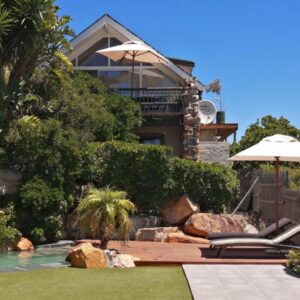 A house with a swimming pool and an umbrella at African Violet Guest Suites in Noordhoek