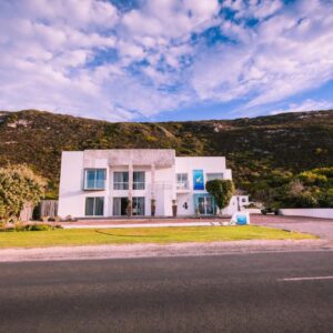 A white house on the side of a road at Agulhas Ocean House in Agulhas