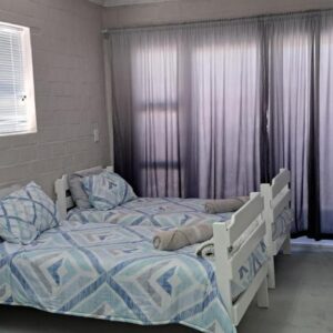 A bedroom with a bed and a bed and a window at AHA Pet Friendly cottage in Agulhas