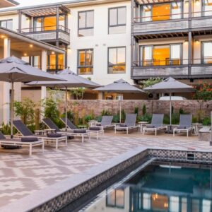 A pool with chairs and umbrellas next to a building at aha The Rex Hotel in Knysna