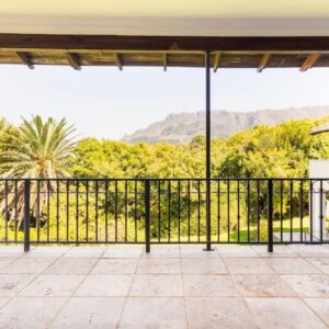 A covered veranda looking over the trees to the mountains at Alphen Drive Apartments in Constantia, Cape Town