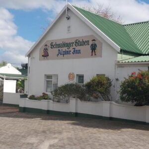 A white building with a green roof and flowers in front at Alpine Inn in George