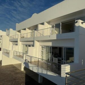 A white building with balconies on the side of it at Ana's Place Apartments in Mossel Bay