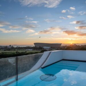 A pool on the roof of a building with the sunset at ANEW Hotel Green Point Cape Town in Cape Town