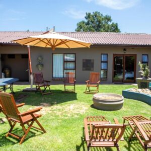 A yard with chairs and an umbrella and a fire pit at Antiqua Guest House in George