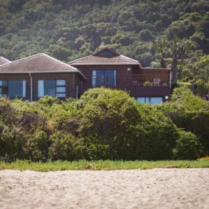 A house sitting on top of a hill next to a beach at Archrock Resort in Plettenberg Bay