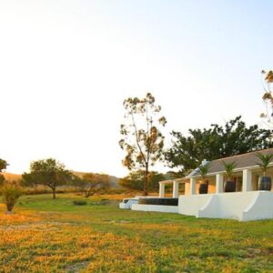 A house in a field with the sun setting behind it at Arnion - Nature Retreat in Clanwilliam