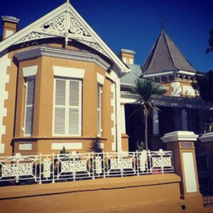 A yellow building with a balcony and a clock tower at Ashanti Gardens Guesthouse in Cape Town