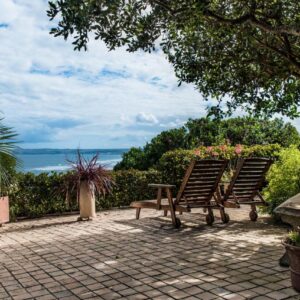 Two chairs and a bench sitting on a brick patio at At Whale-Phin Guest House in Reebok