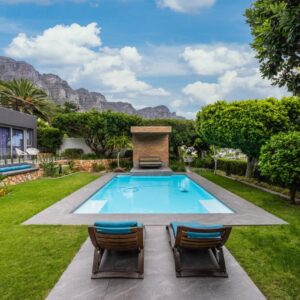 A backyard with a swimming pool and two chairs at Atholl House in Cape Town