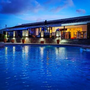 A swimming pool in front of a house at night at Aviators Paradise Guest House in Mossel Bay