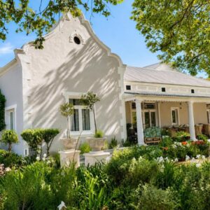 A white house with a garden in front of it at Banhoek Corner Guesthouse in Stellenbosch