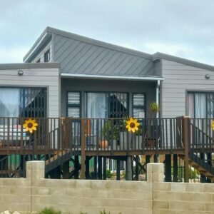 A house with a deck with sunflowers on it at Bedrock Accommodation in Gansbaai