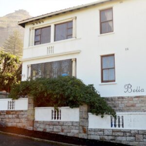 A white house with a stone wall at Bella Ev Guest House in Muizenberg