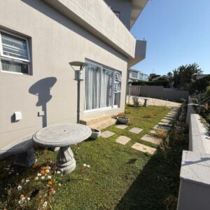 A garden with a table in front of a house at Berg & Baai guesthouse in Plettenberg Bay