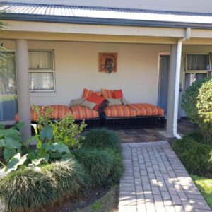 A covered patio with cushioned seating and a garden path at Bethel B&B in George