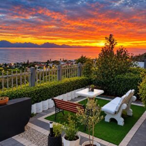 A patio with a table and benches and a sunset at Blessed at Bay Ivy Guest Suite in Mossel Bay