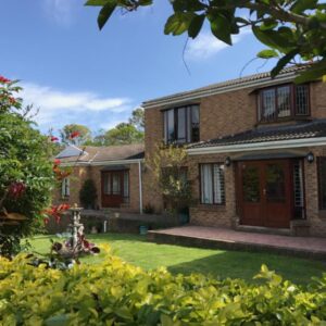 A brick house with a yard with grass at Blue Fern of Knysna in Knysna