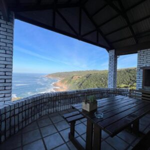 A balcony with a table and a view of the ocean at Blue Whale Resort in George