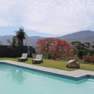A swimming pool with two chairs and mountains in the background at Bontebokskloof in Swellendam