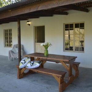 A patio with a wooden table and a bench at Boskloof Swemgat in Clanwilliam