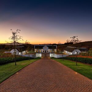 A driveway leading to a house with a sunset in the background at Brookdale Estate - Manor House in Paarl