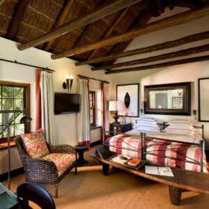 A bedroom with a bed and a table and a chair at Bushmans Kloof Wilderness Reserve and Wellness Retreat in Clanwilliam