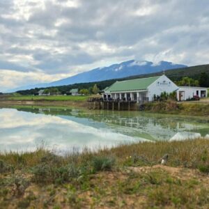 A body of water with a house and mountains in the background at Bydidam Resort in Citrusdal