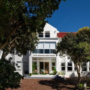 A white house with trees in the foreground at Cape Agulhas Guest House in Agulhas