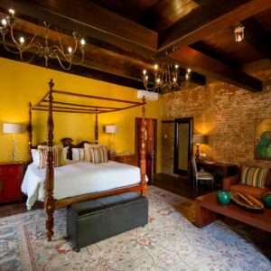 A bedroom with a canopy bed and a living room at Cape Heritage Hotel in Cape Town