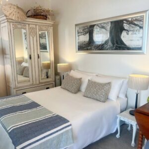 A bedroom with a white bed and a dresser at Cape Town Explorer's Rest in Meadowridge